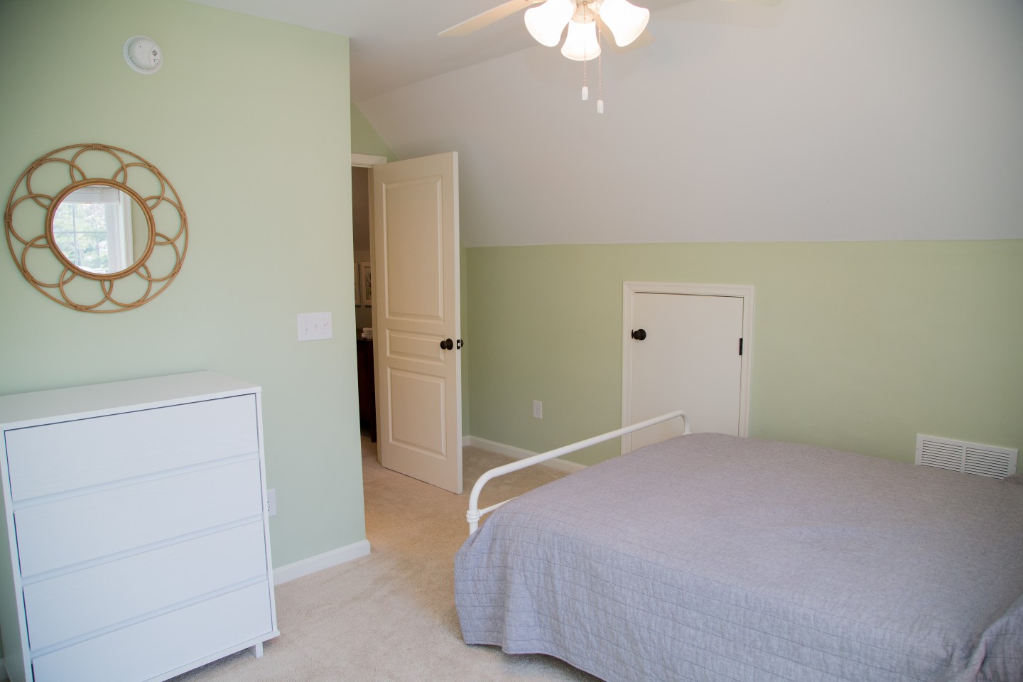 Bedroom with Light Green Wall Paint, Round Flower Style Mirror and White Flat Panel Cabinet