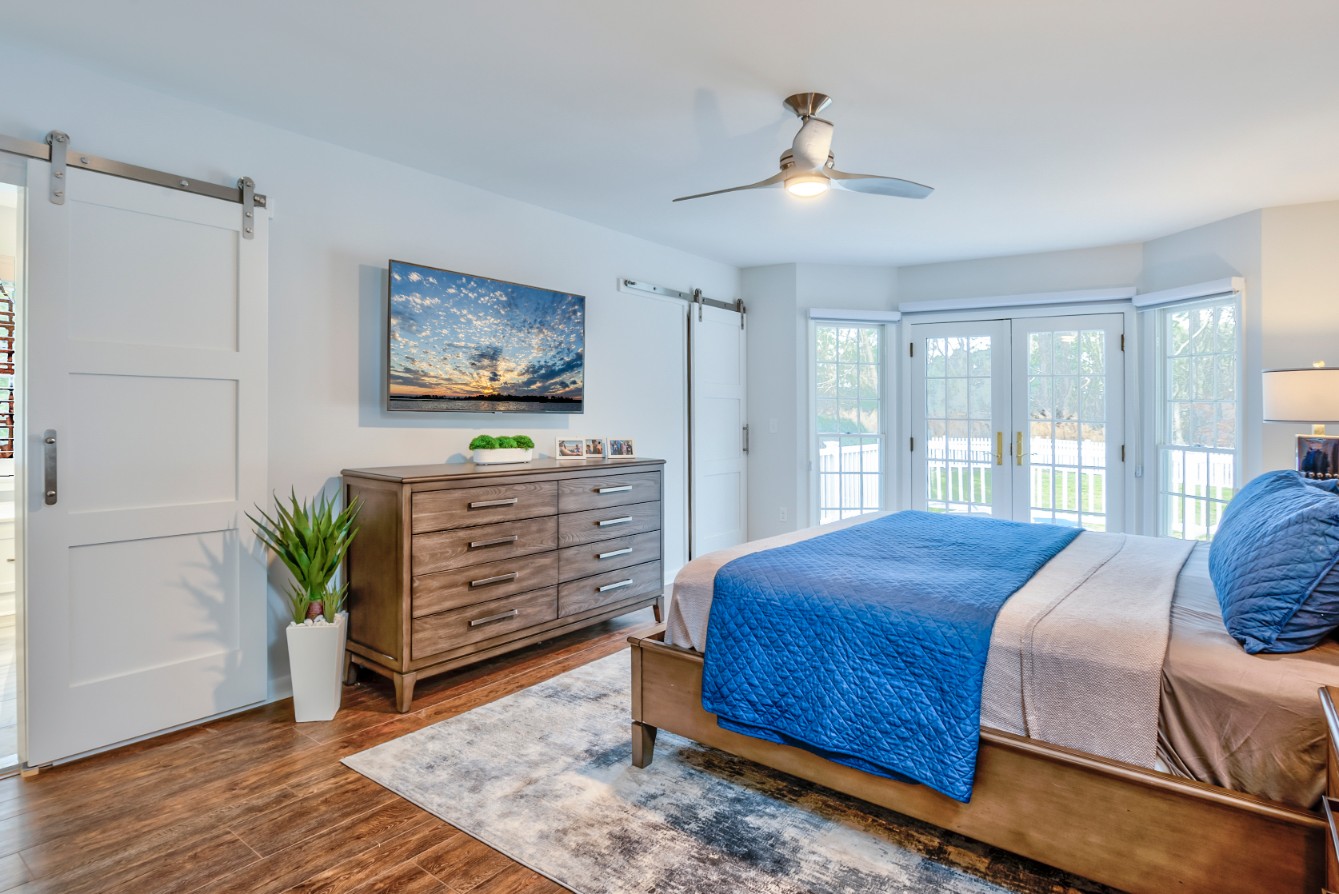 Canal Way Renovation in Bethany Beach DE - Bedroom with Dark Wood Flooring and Wall Mount TV