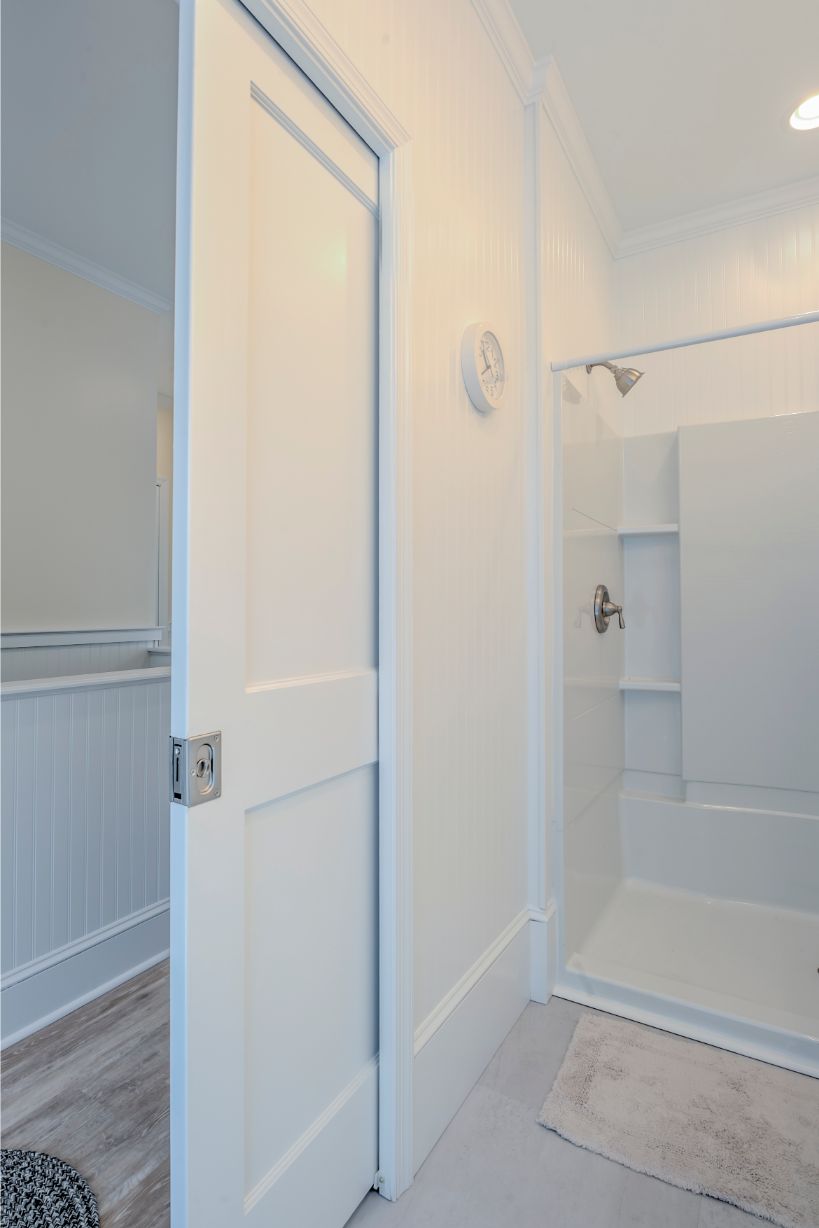 White Sliding Wooden Door Separating Bathroom from Hallway