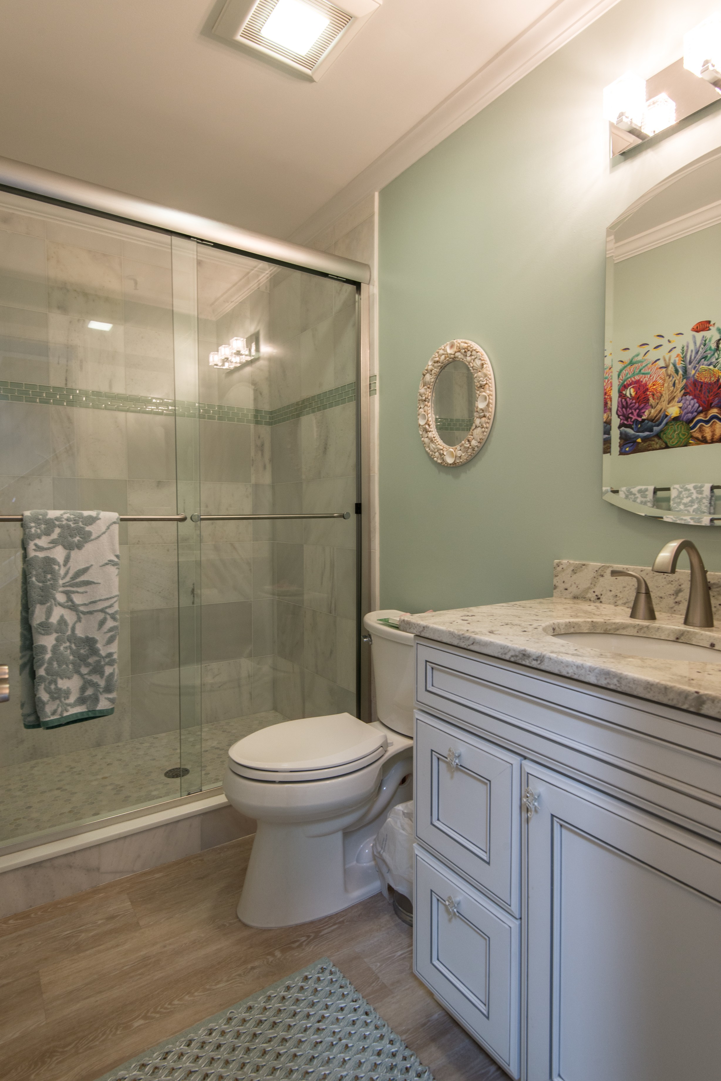 Bathroom Remodel in Kings Grant, Fenwick Island DE with Sliding Glass Shower Doors, Wood Flooring and White Vanity