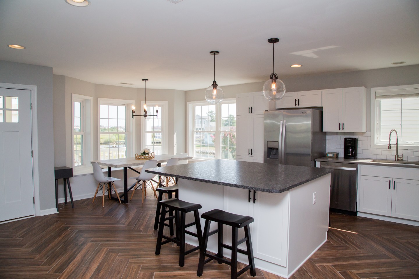 Kitchen with White Cabinets, Center Isle, Dark Granite Countertop and Pendant Lighting