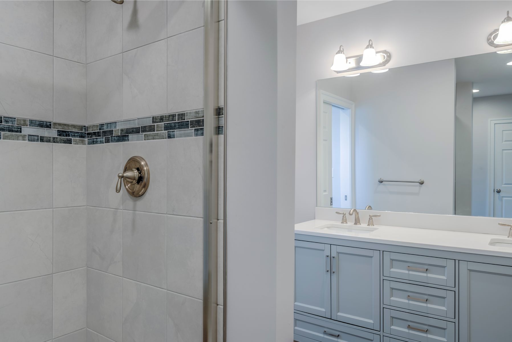 Bathroom Remodel in October Glory, Ocean View DE with White Shower Tiles, Blue Denim Mosaic Accent Tiles and White Vanities